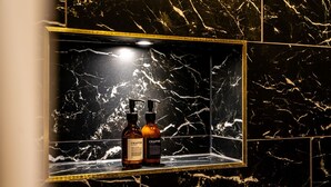 A bathroom with a marble vanity, two bottles of shampoo, and a framed mirror. - An exquisite, brand new studio right in the heart of the city centre (York)