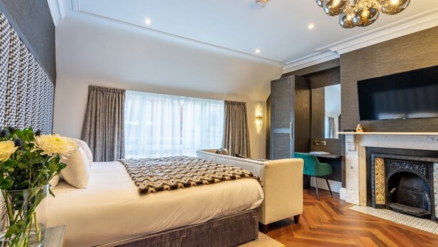 A modern bedroom with a large bed, a fireplace, a TV, and a desk. - An exquisite, brand new studio right in the heart of the city centre (York)