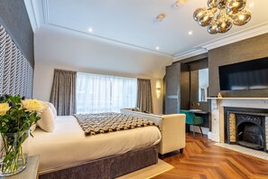 A modern bedroom with a large bed, a fireplace, a TV, and a desk. - An exquisite, brand new studio right in the heart of the city centre (York)