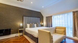 A modern bedroom with a large bed, a sofa, a TV, and a window with curtains. - An exquisite, brand new studio right in the heart of the city centre (York)