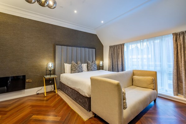 Un dormitorio moderno con una cama grande, un sofá, un televisor y una ventana con cortinas.