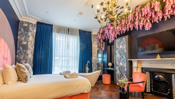 Une chambre à coucher avec un grand lit, une baignoire, une cheminée et un lustre.