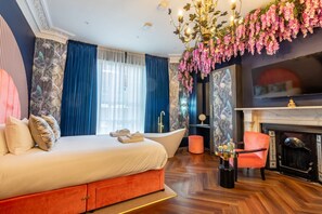 Un dormitorio con una cama grande, una bañera, una chimenea y un candelabro.