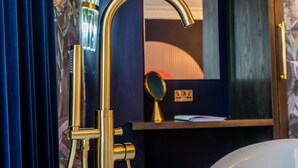 Une salle de bain avec un robinet doré, un miroir et un rideau bleu.
