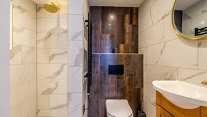 Une salle de bain moderne équipée d’une douche, de toilettes et d’un lavabo.