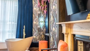 Une salle de bain moderne avec une baignoire sur pieds, un meuble-lavabo avec un miroir et un mur décoratif orné de fleurs suspendues.
