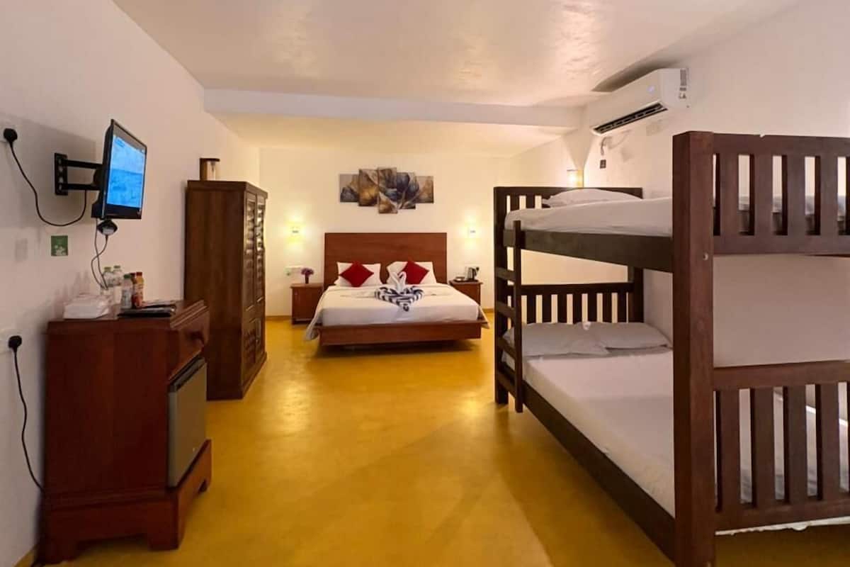 Un dormitorio con una cama litera, un escritorio con computadora, un armario y una cama con almohadas.