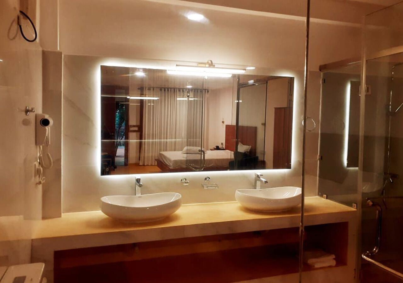 A modern bathroom with two large, round sinks, a large mirror, and a glass shower enclosure.
