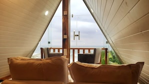 A cozy room with two sofas facing a glass door leading to a balcony with a view of the sea.