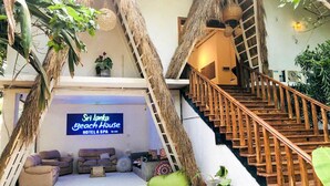 A hotel interior with a staircase, seating area, and a sign for Sri Lanka Beach House Hotel & Spa.