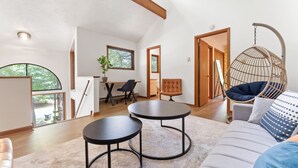A spacious living area with a high ceiling, a hanging chair, a sofa, and a dining table with chairs. - Hot Tub, Fire Pit, Game Room; 4BR Cozy Poconos! (East Stroudsburg)
