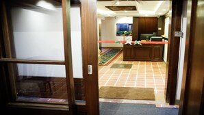 Ein Hotel Eingangsbereich mit Fliesenboden, einer Rezeption und einem Teppichbereich.
