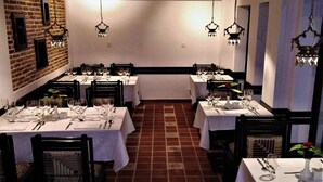Ein Restaurant mit Backsteinwänden, mehreren gedeckten Tischen und hängenden Kronleuchtern.