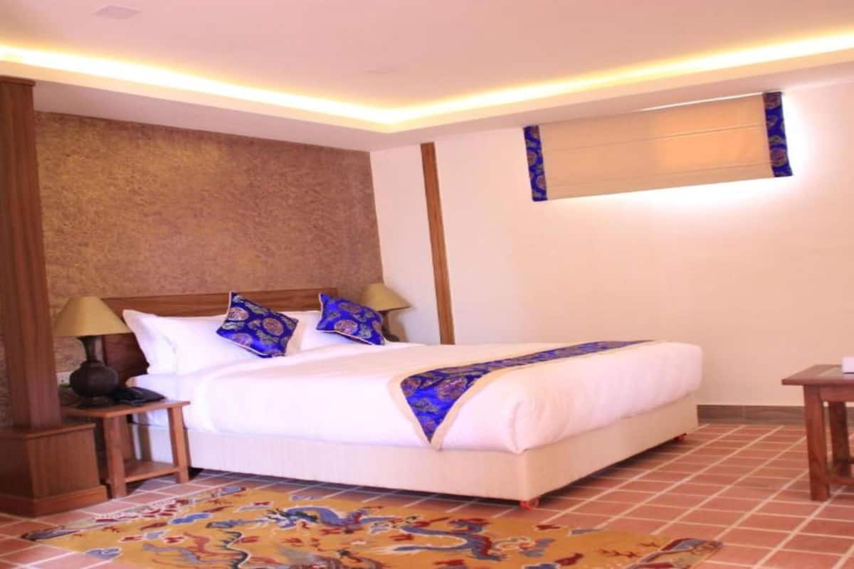 A hotel room with a bed, nightstands, a small table, and a patterned rug.