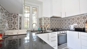 A modern kitchen with white cabinets, a black countertop, a stove, and a coffee maker.