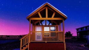 Una cabaña de madera con balcón y escaleras, al atardecer.