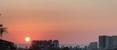 Une vue d’une ville côtière au coucher du soleil, avec des bâtiments et un ciel dégagé.