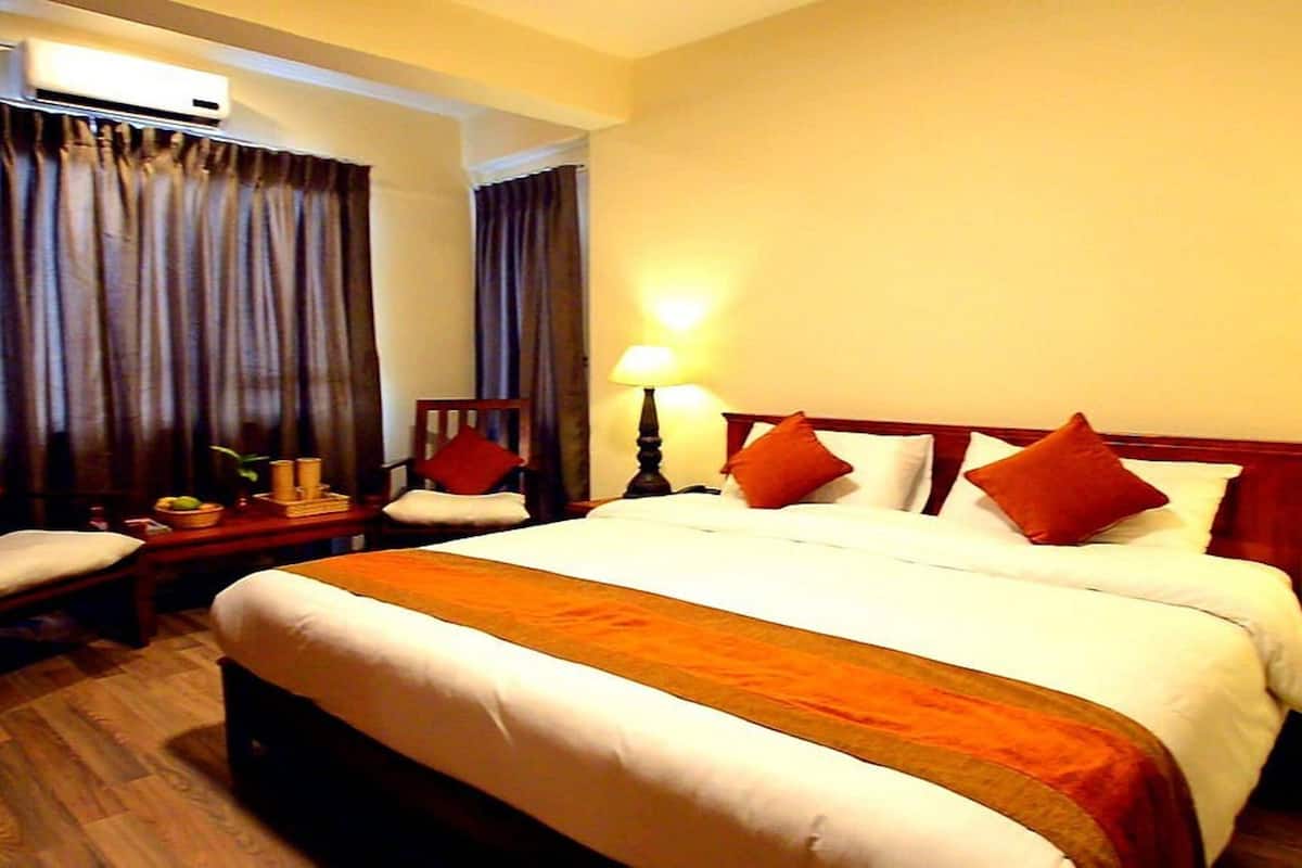 A hotel room with a large bed, two bedside tables with lamps, a chair, and a desk with a lamp.