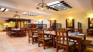 A dining area with wooden tables and chairs, a chandelier, and artwork on the walls. - MeroStay 253 GT Hotel (Kathmandu)