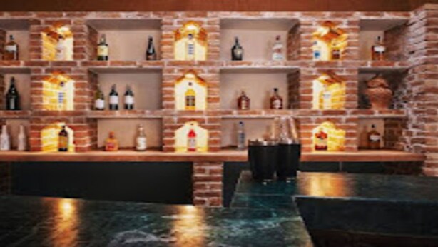 A bar area with multiple shelves of bottles, a bar counter, and seating. - MeroStay 253 GT Hotel (Kathmandu)