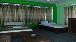 A room with two beds, a wardrobe, and a small table with a remote control. - MeroStay 122 Natraj Restaurant &Bar (Kathmandu)