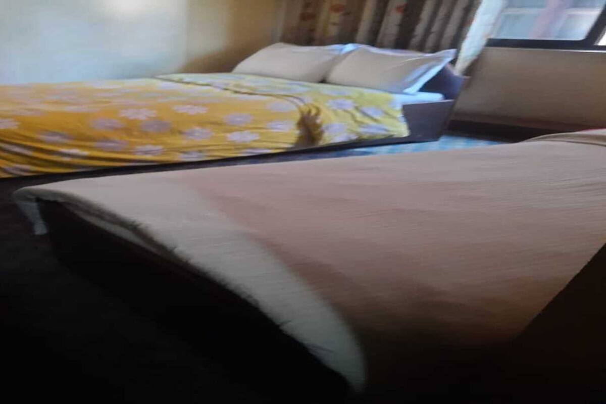 Une chambre d’hôtel avec deux lits, dont l’un est recouvert d’une couvre-lit à motifs floraux et l’autre d’une simple couverture.