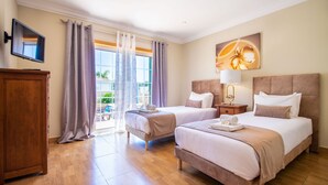 Une chambre d’hôtel avec deux lits, une télévision, une armoire en bois et une grande fenêtre avec des rideaux.