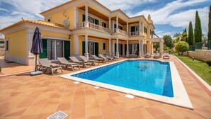 Ein großes Haus mit Swimmingpool, mehreren Balkonen und einem gepflegten Rasen.