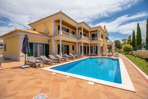 Uma casa grande com piscina, várias varandas e um gramado bem cuidado.