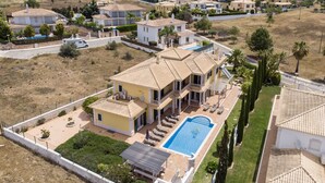 Une grande maison avec une piscine, plusieurs balcons et un jardin bien entretenu.