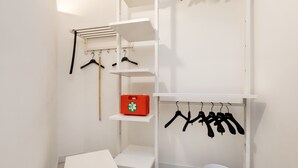 Una habitación con un armario blanco, un tendedero y un cubo blanco.