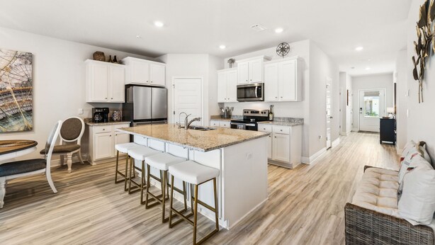 A modern kitchen with white cabinetry, stainless steel appliances, and a central island with bar stools. - Windmark Beach! Heated Pool, Water View, Loaded, Golf Cart! Weekly Stay Disc! (Port St. Joe)