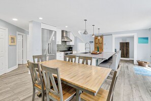 A modern kitchen with a central island, stainless steel appliances, and a dining area with wooden furniture.