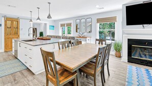 A modern kitchen with a central island, dining area, and a fireplace.