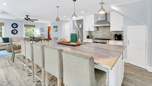A modern kitchen with white cabinets, a large island, and pendant lighting.