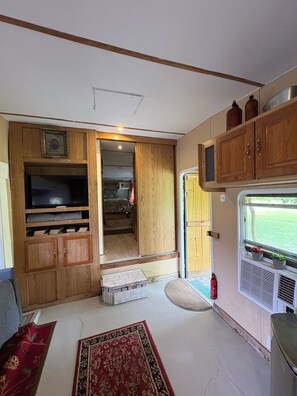 Un intérieur de camping-car compact comprenant un coin cuisine, un téléviseur et un petit espace salon.