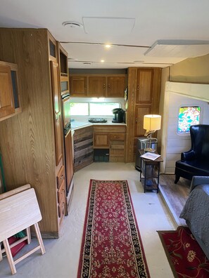 Un espacio habitable compacto con kitchenette, zona de comedor y área de estar con sofá y sillón.