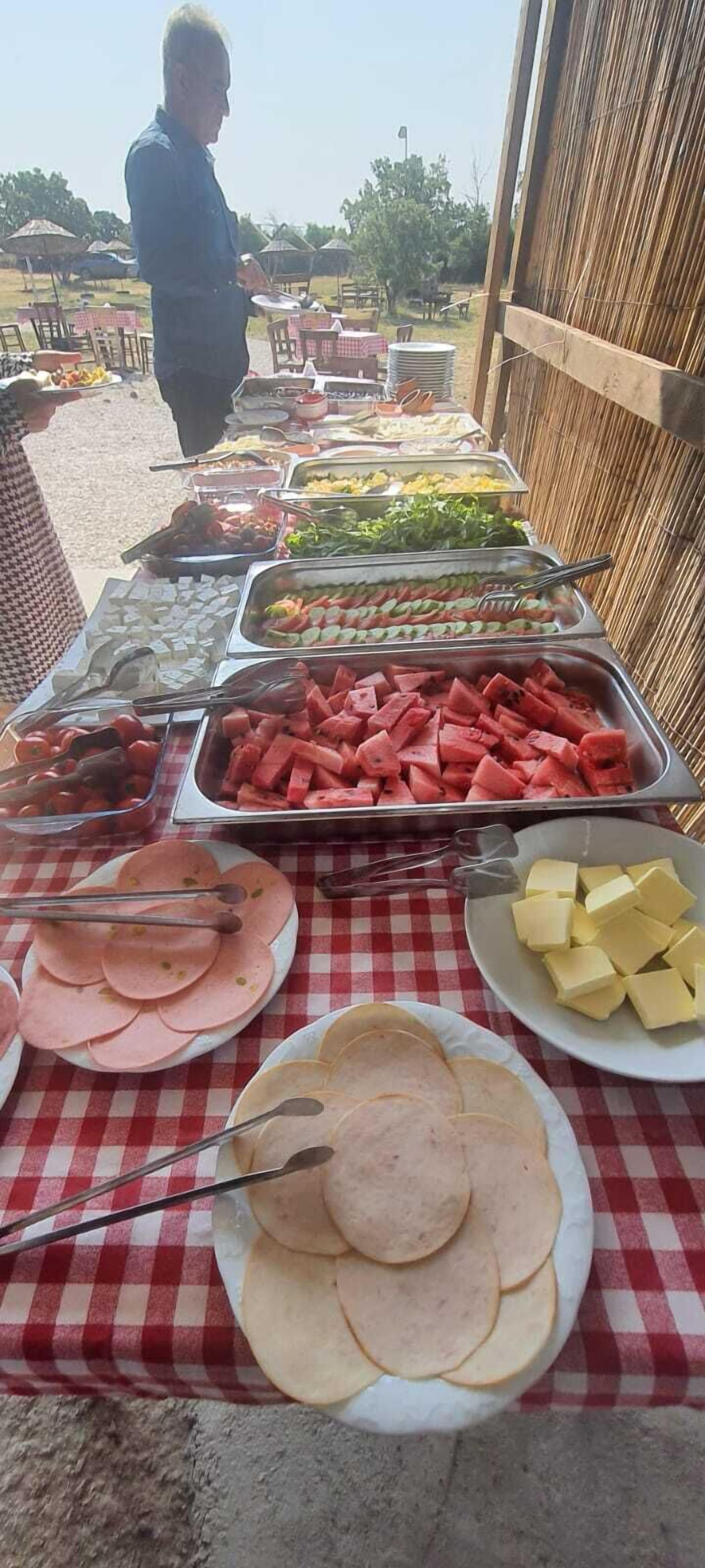 A buffet table with various food items including sliced meats, vegetables, and fruits.