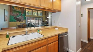 Une cuisine avec des meubles de rangement en bois, un évier et un lave-vaisselle.