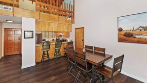 Une cuisine spacieuse avec un plafond en bois, un coin repas avec une table et des chaises en bois, et un tableau accroché au mur.