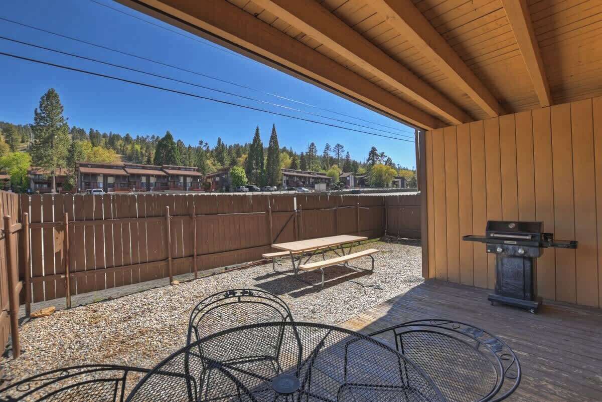 An outdoor patio with a wooden ceiling, a barbecue grill, and a picnic table.