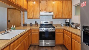 Una cocina moderna con armarios de madera, estufa de acero inoxidable y horno empotrado.