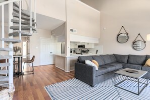 Uma sala de estar moderna com um sofá cinza, uma mesa de centro e uma escada com um arranhador para gatos.
