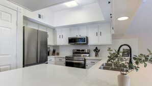 Een moderne keuken met witte kasten, roestvrijstalen apparatuur en een centraal eiland.