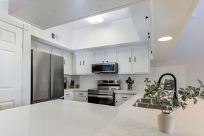 A modern kitchen with white cabinetry, stainless steel appliances, and a central island.