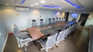 Een vergaderzaal met een lange tafel, stoelen en een televisiescherm.