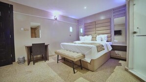 Een slaapkamer met een bed, nachtkastjes, een bankje, een bureau en een spiegel.