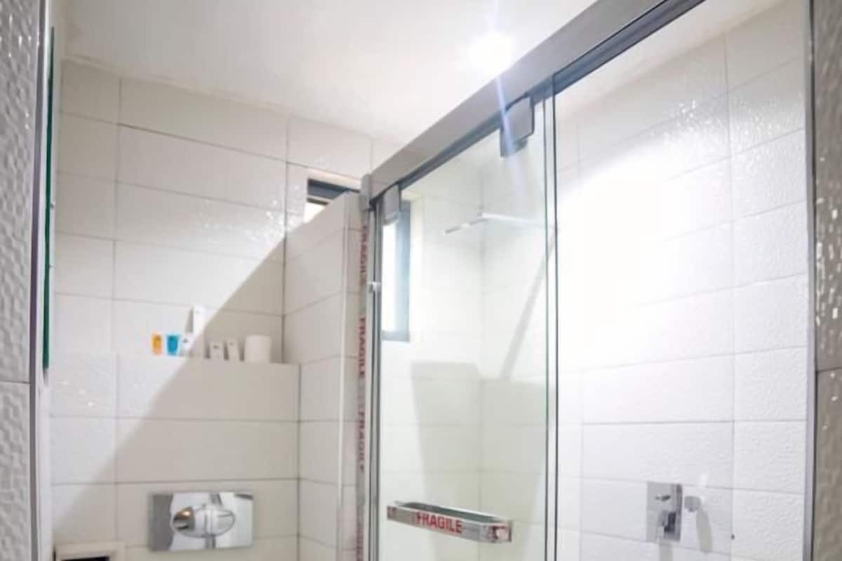 A modern bathroom with a glass-enclosed shower, a white sink, and a toilet.
