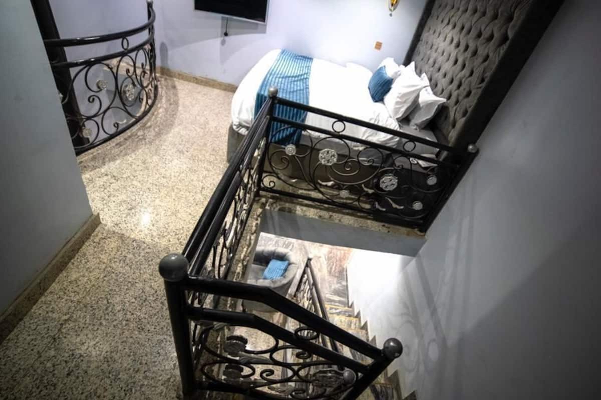 A staircase with ornate metal railings leading to a bedroom with a bed and a headboard.