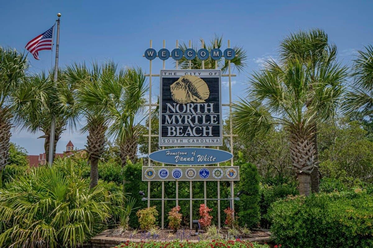 Welkomstbord voor North Myrtle Beach, South Carolina, met een Amerikaanse vlag en palmbomen.